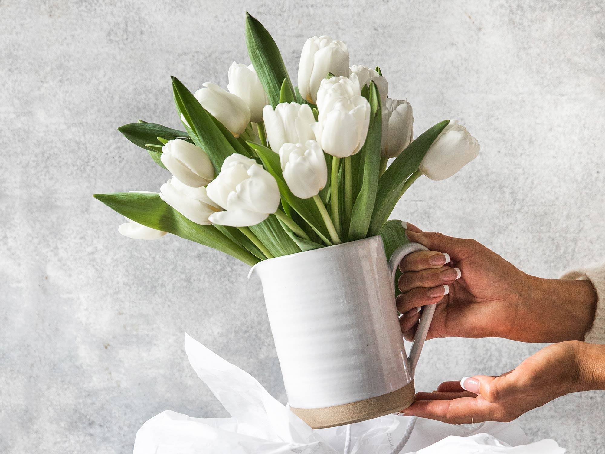 white silo pitcher with tulips coming out of a gift bag