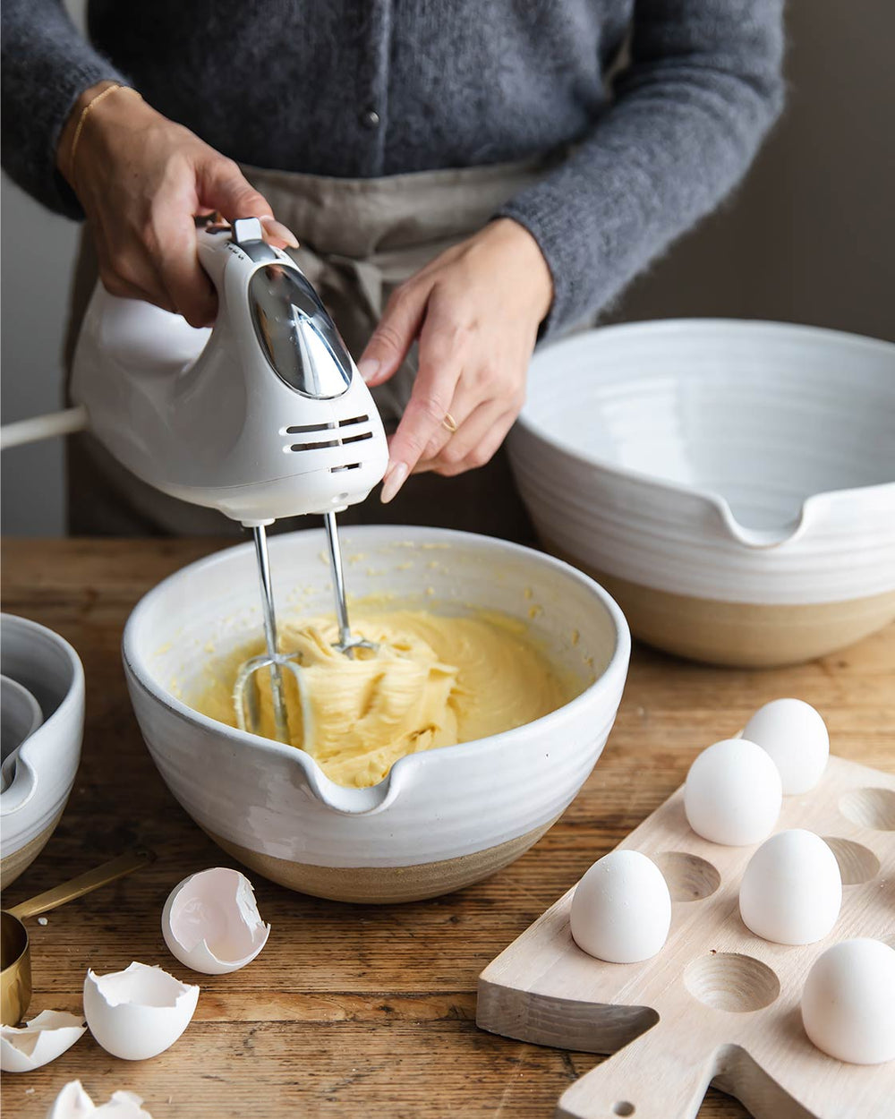 A mixer beats batter in a large pantry bowl next to a tray of eggs