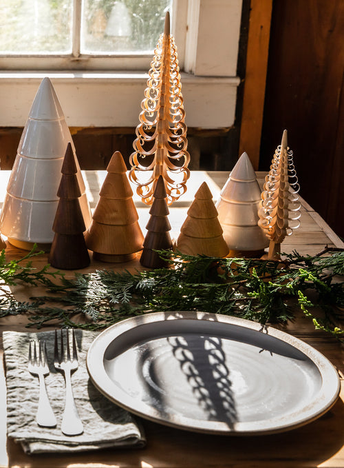 Decorative Christmas trees on a table with a plate and cutlery.