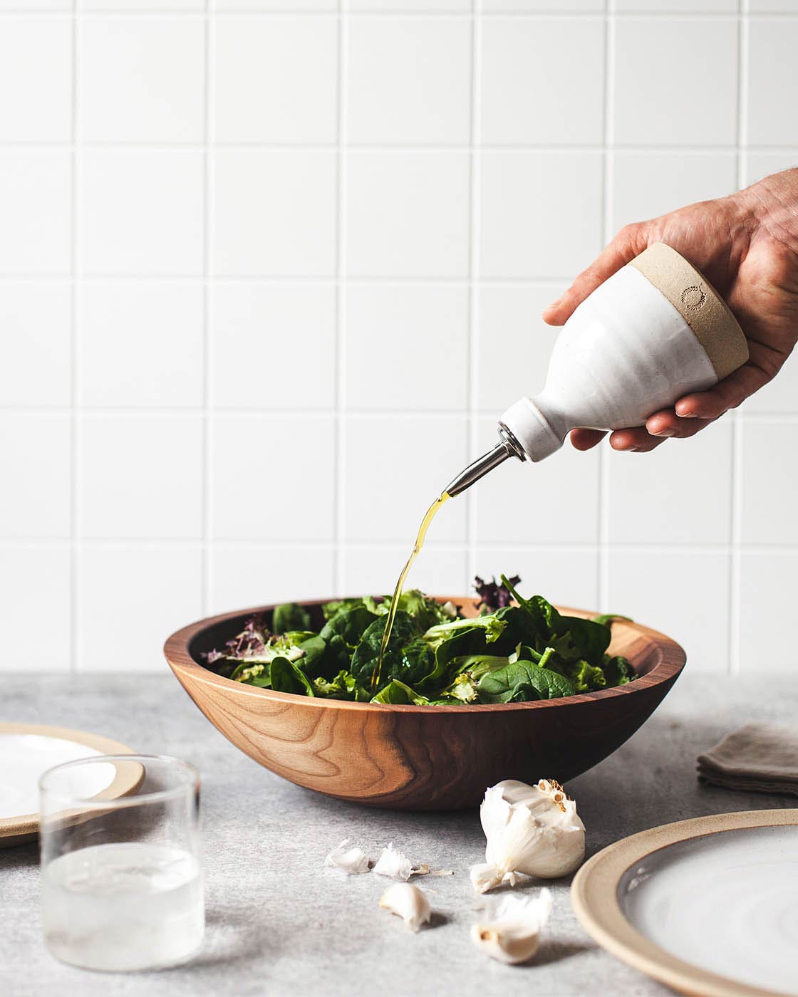 Handmade pottery olive oil pour bottle being drizzled on a salad