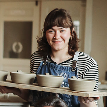 Person holding a tray with ceramic bowls in a kitchen setting