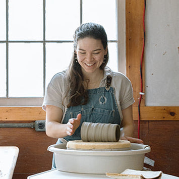 Person working with clay on a pottery wheel in a studio setting