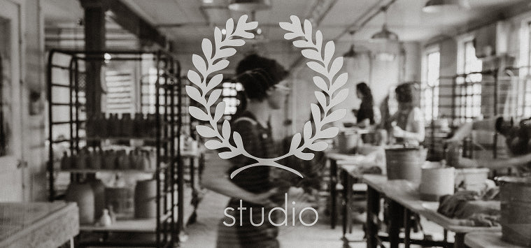 Black and white image of a pottery studio with people working, featuring a decorative logo overlay.